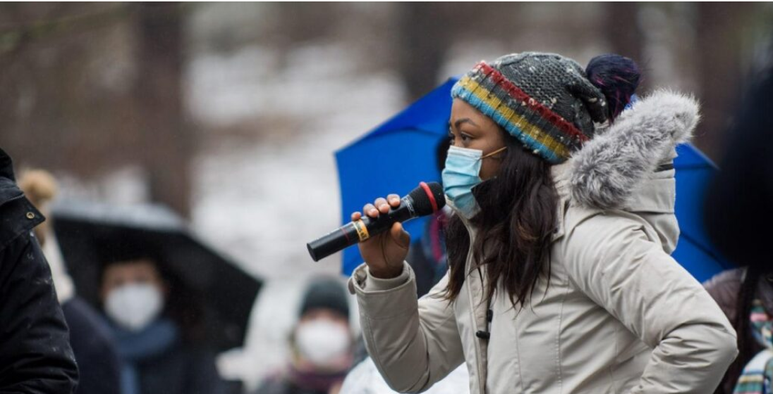 Protester speaking into a microphone to a crowd that has gathered.