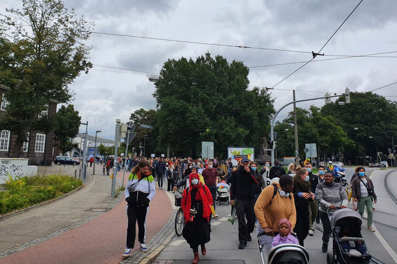 Protestors marching down a street, many pushing strollers.