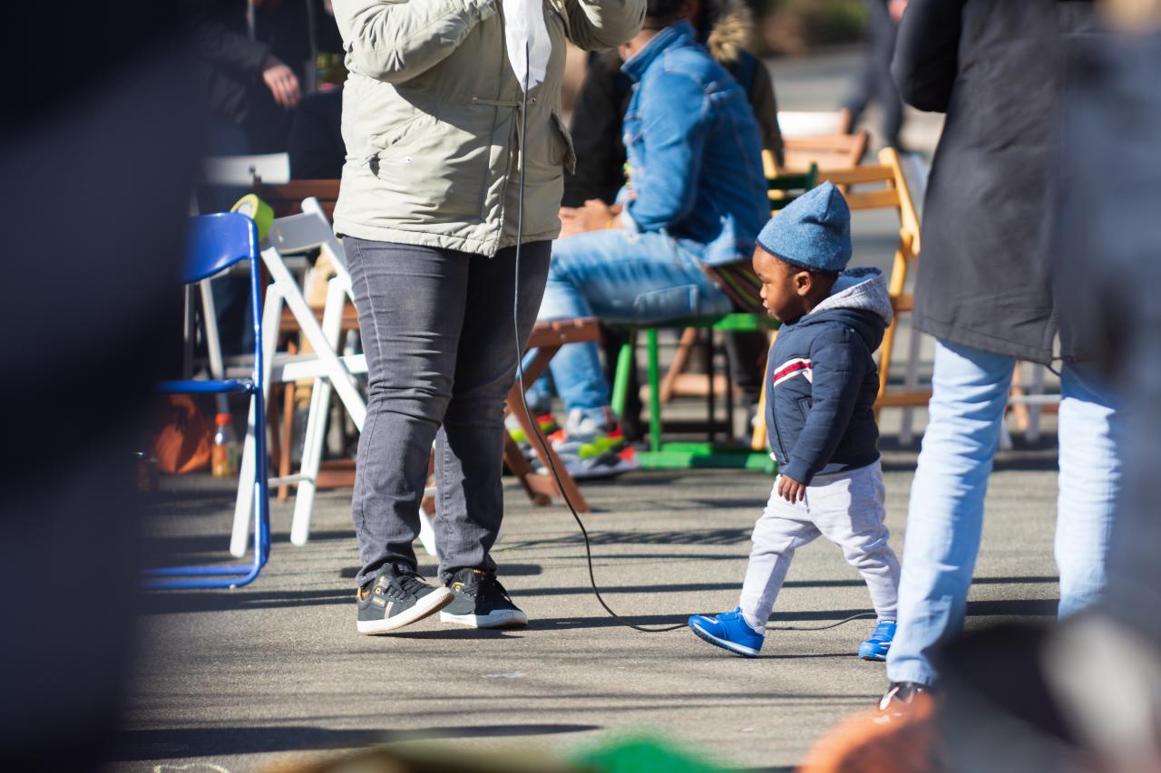 A young child walking around the feet of the protestors.